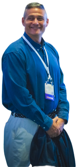 Tony Siragusa at a conference, standing with his hands clasped, an instructor ribbon on his badge.