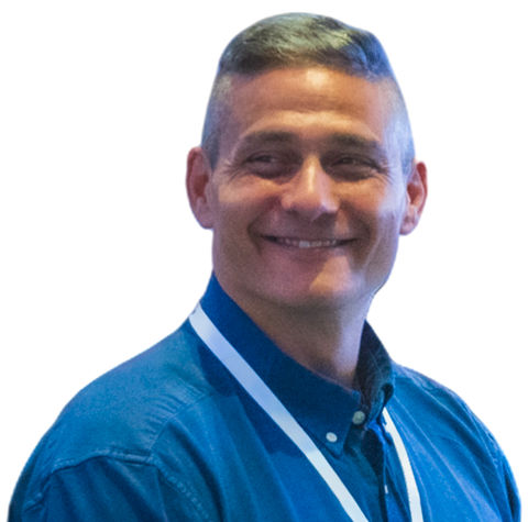 Tony Siragusa at a conference, smiling, in a blue button-down shirt.